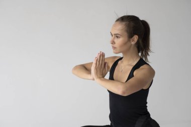 Genç bir kadın stüdyoda yoga yapıyor. Siyah spor giysili zayıf genç kız mavi bir minderde yoga çalışması yapıyor. Vücut ve zihinsel gelişim arasındaki sağlıklı yaşam ve doğal denge kavramı.