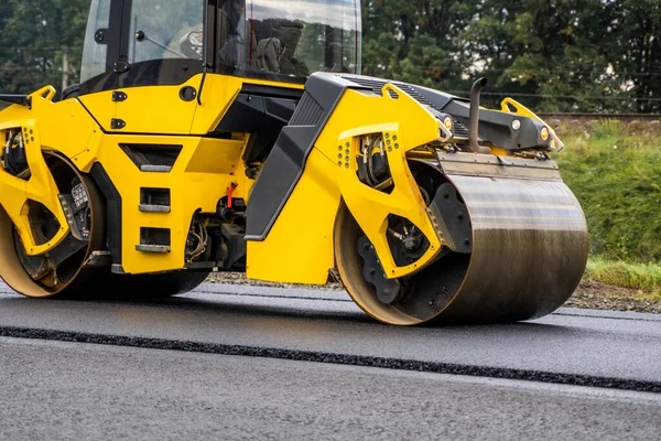 Asphalt road roller with heavy vibration roller compactor press new hot asphalt on the roadway on a road construction site. Heavy Vibration roller at asphalt pavement working. Repairing.