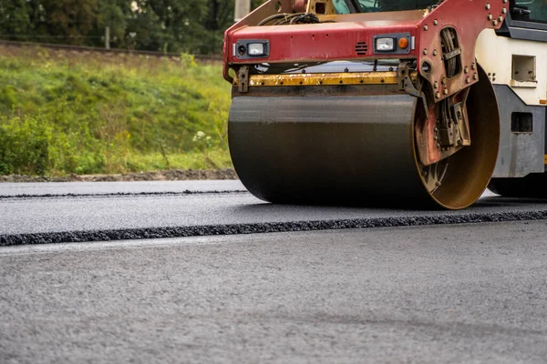 Asfalt road roller z ciężkimi wibracjami rolki zagęszczarki naciśnij nowy gorący asfalt na jezdni na placu budowy dróg. Ciężki wałek wibracyjny na asfaltowej nawierzchni działa. Naprawa. — Zdjęcie stockowe