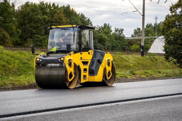 Asphalt road roller with heavy vibration roller compactor press new hot asphalt on the roadway on a road construction site. Heavy Vibration roller at asphalt pavement working. Repairing.