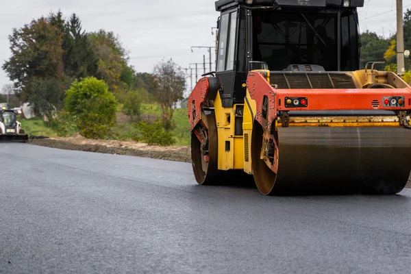 Asfalt road roller z ciężkimi wibracjami rolki zagęszczarki naciśnij nowy gorący asfalt na jezdni na placu budowy dróg. Ciężki wałek wibracyjny na asfaltowej nawierzchni działa. Naprawa. — Zdjęcie stockowe