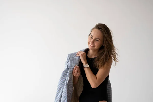 Portrait de jeune femme maigre brune pose en sous-vêtements noirs et veste bleue, assis sur une petite échelle blanche en studio blanc. Tests de mannequin de jolie fille en vêtements de base sur cyclorama. — Photo