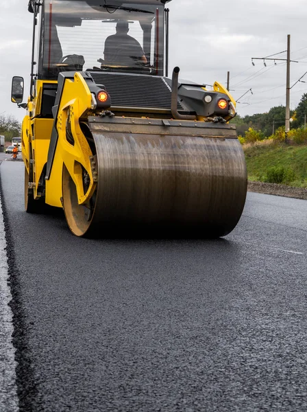 Asphalt road roller with heavy vibration roller compactor press new hot asphalt on the roadway on a road construction site. Heavy Vibration roller at asphalt pavement working. Repairing.