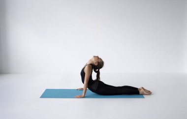 Yoga yapan, yalan söyleyen ve Kobra pozu veren genç bir kadın Bhujangasana egzersizi yapıyor. Siyah spor giyimli çekici bir kız. Güzel, formda bir yogacı kadın yoga yapıyor, asana bhujangasana.