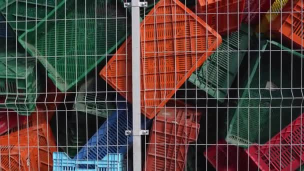 Gamla plastlådor i ett lager som skräp bakom metallnätstaketet. — Stockvideo