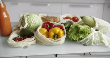 Sebzeler, tekrar kullanılabilir eko-pamuklu poşetlerdeki meyveler masada. Sıfır atık alışveriş kavramı. Plastiksiz ürünler. Çoklu kullanım, yeniden kullanım, geri dönüşüm. Domatesli, biberli, ekmekli çevre dostu tuval..