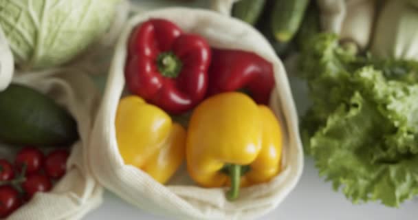 Warzywa, owoce w eko-bawełnianych workach wielokrotnego użytku na stole. Zero marnotrawienia. Plastikowe przedmioty. Wielorazowe użycie, ponowne użycie, recykling. Ekologiczne płótno torba spożywcza z pomidorami, pieprzem, chlebem. — Wideo stockowe