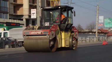 KYIV, UKRAINE - 10 Eylül 2020: Ağır asfalt yol silindirli ağır titreşimli paten sıkıştırıcısı, bir cadde üzerindeki yol inşaatında yeni bir sıcak asfalta baskı yapıyor..