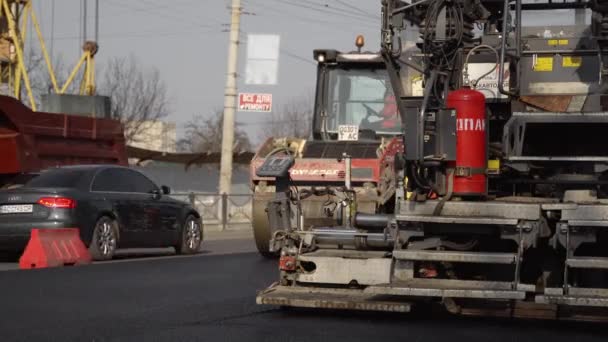 KYIV, UKRAINE - 10 de setembro de 2020: Rolo de estrada de asfalto pesado com compactador de rolos de vibração pesada que pressiona nova máquina de pavimentação de asfalto e asfalto quente em um canteiro de obras de estrada em uma rua. — Vídeo de Stock