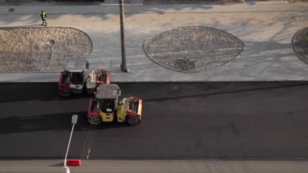 KYIV, UKRAINE - 10 september 2020: Två tunga asfalterade vägvältar med tung vibrationsvält som pressar ny het asfalt på vägbanan på en vägbygge på en gata. — Stockvideo
