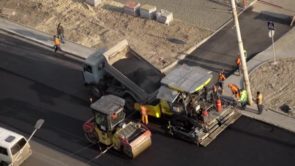 KYIV, UCRANIA - 10 de septiembre de 2020: Rodillo de carretera de asfalto pesado con compactador de rodillos de vibración pesada que presiona una nueva máquina de asfalto y asfalto caliente en un sitio de construcción de carreteras en una calle. — Vídeo de stock