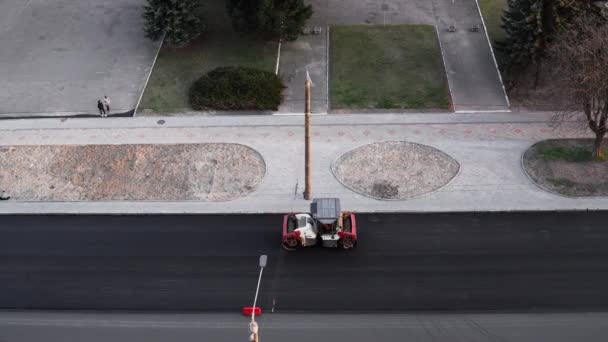 KYIV, UCRANIA - 10 de septiembre de 2020: Rodillo de carretera de asfalto pesado con compactador de rodillos de vibración pesada que presiona el nuevo asfalto caliente en la carretera en un sitio de construcción de carreteras en una calle. — Vídeo de stock