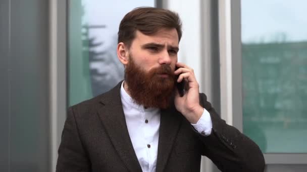 Businessman talking on the phone in financial district. Portrait of a Young urban professional man using smart phone over office building. Business man talking on his smartphone outdoors. Technology. — Stock Video