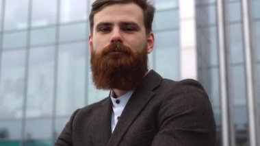 Finans bölgesindeki ofis binasında ceketli yakışıklı bir işadamının portresi. Genç sakallı iş adamı. Resmi giyinmiş başarılı bir girişimci..