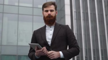 Finans bölgesindeki ofis binasında ceketli yakışıklı bir işadamının portresi. Genç sakallı iş adamı. Resmi giyinmiş başarılı bir girişimci..