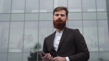 Finans bölgesindeki ofis binasında ceketli yakışıklı bir işadamının portresi. Genç sakallı iş adamı. Resmi giyinmiş başarılı bir girişimci..