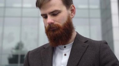 Finans bölgesindeki ofis binasında ceketli yakışıklı bir işadamının portresi. Genç sakallı iş adamı. Resmi giyinmiş başarılı bir girişimci..