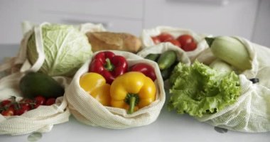 Sebzeler, tekrar kullanılabilir eko-pamuklu poşetlerdeki meyveler masada. Sıfır atık alışveriş kavramı. Plastiksiz ürünler. Çoklu kullanım, yeniden kullanım, geri dönüşüm. Domatesli, biberli, ekmekli çevre dostu tuval..
