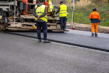 KYIV, UKRAINE - 25 Eylül 2020: Karayolu şantiyesine yeni asfalt döşeyen endüstriyel asfalt kaldırım makinesi.