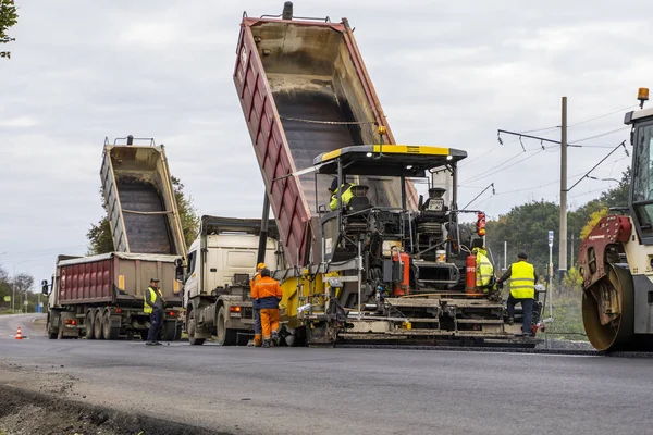 KYIV, UKRAINE - 25 Eylül 2020::: Ağır titreşimli asfalt yol silindiri, yeni asfalt ve asfalt kaldırım taşıma makinesine baskı yapan ağır titreşimli paten sıkıştırıcısı.