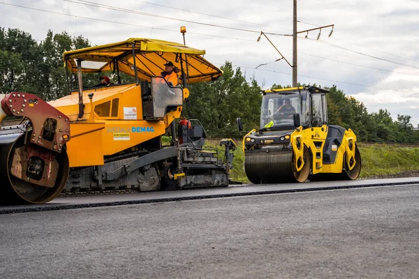 KYIV, UKRAINE - 25 września 2020:: Ciężki asfaltowy wałek drogowy z ciężkim zagęszczaczem wibracyjnym, który wciska nowy gorący asfalt i nawierzchnię asfaltową na budowie drogi na ulicy. — Zdjęcie stockowe