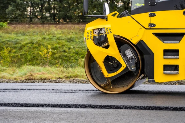 Asphalt road roller with heavy vibration roller compactor press new hot asphalt on the roadway on a road construction site. Heavy Vibration roller at asphalt pavement working. Repairing.