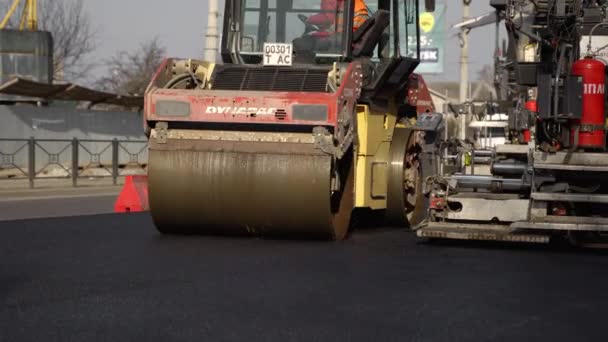 KYIV, UKRAINE - 10 września 2020: Ciężki asfaltowy wałek drogowy z ciężkim zagęszczaczem wibracyjnym, który wciska nowy gorący asfalt i nawierzchnię asfaltową na budowie drogi na ulicy. — Wideo stockowe
