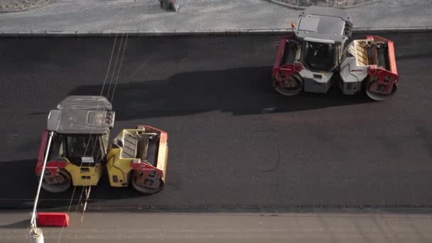 KYIV, UKRAINE - 10 september 2020: Twee zware asfaltwals met zware trilwals compactor die nieuw heet asfalt op de weg persen op een bouwplaats aan een straat. — Stockvideo