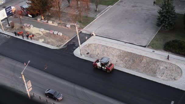 КИЕВ, УКРАИНА - 10 сентября 2020 года: Тяжелый асфальтовый дорожный каток с тяжелым вибрационным роликовым уплотнителем, который нажимает новый горячий асфальт на дорожном полотне на дорожном строительстве на улице. — стоковое видео