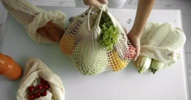 Kadın, tekrar kullanılabilir sebzeli sebzeli sebzeli, biberli, domatesli ve salatalıklı salatayı mutfaktan alır. Sıfır atık, plastiksiz konsept, market alışverişi. Pamuk tüccarı..
