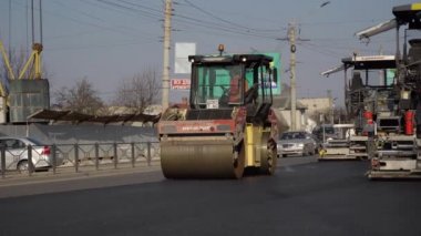 KYIV, UKRAINE - 10 Eylül 2020: Ağır asfalt yol silindirli ağır titreşimli paten sıkıştırıcısı, bir cadde üzerindeki yol inşaatında yeni bir sıcak asfalta baskı yapıyor..