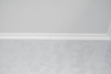 Gri boyalı duvarları olan bir odada beyaz bir kaide. Tavanla odadaki duvar arasındaki köşenin dekorasyonu. Tavan döşemesi iç kısımda. Köşenin ayrıntıları.