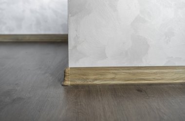 Tahta desenli plastik süpürgelikle kaplanmış. Yeni döşenmiş ahşap döşeme ve süpürgelikler. Modern tasarım. Koyu ahşap meşe parkedeki plastik kaideleri kapatın..