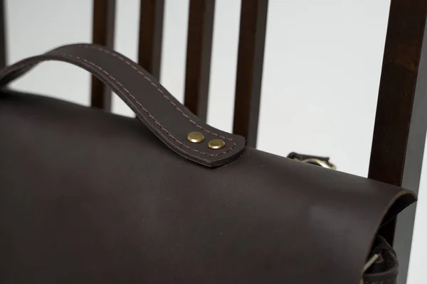 Szczegóły brązowej męskiej torby na ramię na dokumenty i laptopa na brązowym krześle z białym tłem. Skórzana walizka męska, torby kurierskie, skórzana torba, ręcznie robiona walizka. — Zdjęcie stockowe