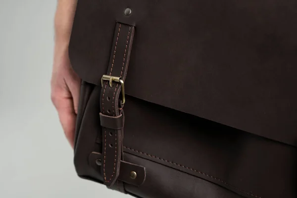 Détails du sac bandoulière en cuir pour homme marron pour un document et un ordinateur portable sur les épaules d'un homme en chemise bleue et un jean avec un fond blanc. Cartable, mallette en cuir pour homme. — Photo