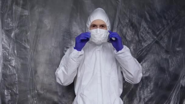 Lekarz w białym kombinezonie ochronnym, masce, okularach i gumowych rękawiczkach jest gotowy pomóc ludziom, podczas gdy zagrożenie pandemią koronawirusów. Epidemia, pandemia koronawirusa covid 19. Lekarz w respiratorze. — Wideo stockowe