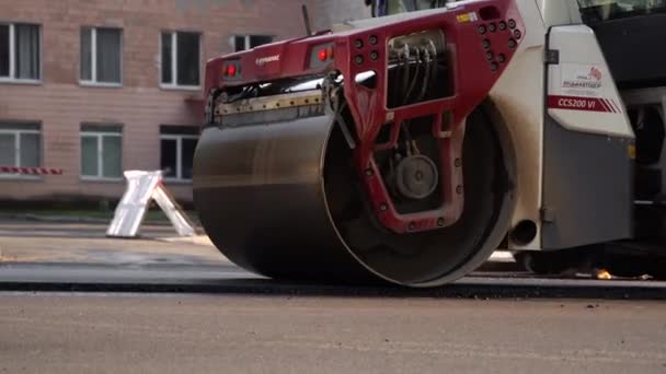 КИЕВ, УКРАИНА - 10 сентября 2020 года: Тяжелый асфальтовый дорожный каток с тяжелым вибрационным роликовым уплотнителем, который нажимает новый горячий асфальт на дорожном полотне на дорожном строительстве на улице. — стоковое видео