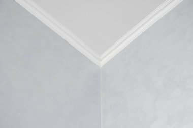Gri boyalı duvarları olan bir odada beyaz bir kaide. Tavanla odadaki duvar arasındaki köşenin dekorasyonu. Tavan döşemesi iç kısımda. Köşenin ayrıntıları.