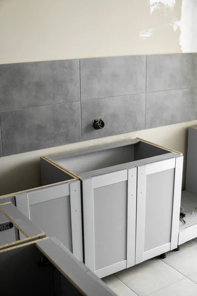 Lagere aangepaste keukenkasten installatie met een meubelgevel mdf. Gray modulaire keuken van spaanplaat materiaal op een verschillende stadia van de installatie. Een frame meubelfronten mdf profiel. — Stockfoto