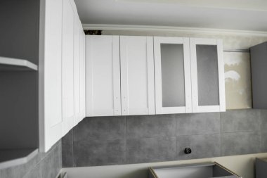 Mobilya cepheli özel mutfak dolapları kurulumu. Gri modüler mutfak, çeşitli kurulum aşamalarındaki çip malzemelerinden. Bir çerçeve mobilya MDF profilinin önünde.