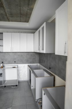 Mobilya cepheli özel mutfak dolapları kurulumu. Gri modüler mutfak, çeşitli kurulum aşamalarındaki çip malzemelerinden. Bir çerçeve mobilya MDF profilinin önünde.