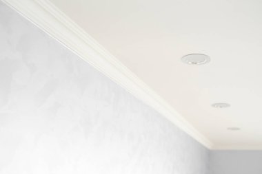 Gri boyalı duvarları olan bir odada beyaz bir kaide. Tavanla odadaki duvar arasındaki köşenin dekorasyonu. Tavan döşemesi iç kısımda. Köşenin ayrıntıları.