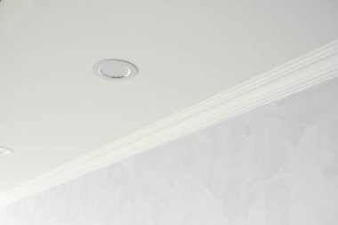 Gri boyalı duvarları olan bir odada beyaz bir kaide. Tavanla odadaki duvar arasındaki köşenin dekorasyonu. Tavan döşemesi iç kısımda. Köşenin ayrıntıları.