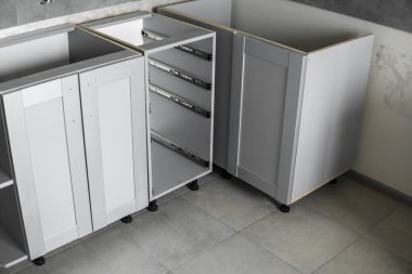 Mobilya cepheli mutfak dolapları döşemesi. Gri modüler mutfak, çeşitli kurulum aşamalarındaki çip malzemelerinden. Bir çerçeve mobilya MDF profilinin önünde.
