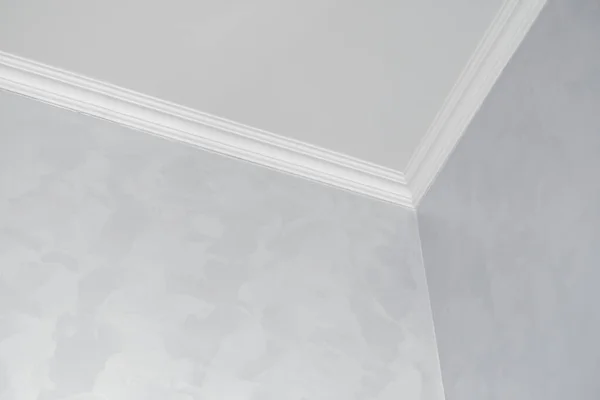 Techo blanco con zócalo blanco en una habitación con paredes pintadas de gris. Decoración de la esquina entre el techo y la pared en la habitación. Moldeo de techo en el interior. Detalle de esquina. — Foto de Stock