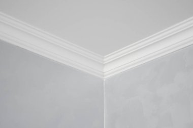 Gri boyalı duvarları olan bir odada beyaz bir kaide. Tavanla odadaki duvar arasındaki köşenin dekorasyonu. Tavan döşemesi iç kısımda. Köşenin ayrıntıları.