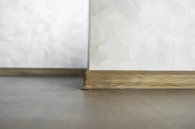 Tahta desenli plastik süpürgelikle kaplanmış. Yeni döşenmiş ahşap döşeme ve süpürgelikler. Modern tasarım. Koyu ahşap meşe parkedeki plastik kaideleri kapatın..
