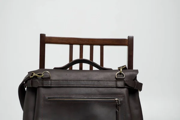 Barna férfi válltáska egy dokumentumhoz és laptop egy barna széken fehér háttérrel. Férfi bőrönd, futártáska, bőrönd, kézzel készített aktatáska. — Stock Fotó