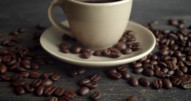 Ahşap masaya saçılmış kahve çekirdekleri ile bir fincan kahve. Bir fincan taze sade kahve. Taze Arap usulü kavrulmuş kahve çekirdekleri. Harika bir sabah başlangıcı. Espresso, americano, doppio.
