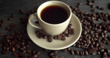 Ahşap masaya saçılmış kahve çekirdekleri ile bir fincan kahve. Bir fincan taze sade kahve. Taze Arap usulü kavrulmuş kahve çekirdekleri. Harika bir sabah başlangıcı. Espresso, americano, doppio.